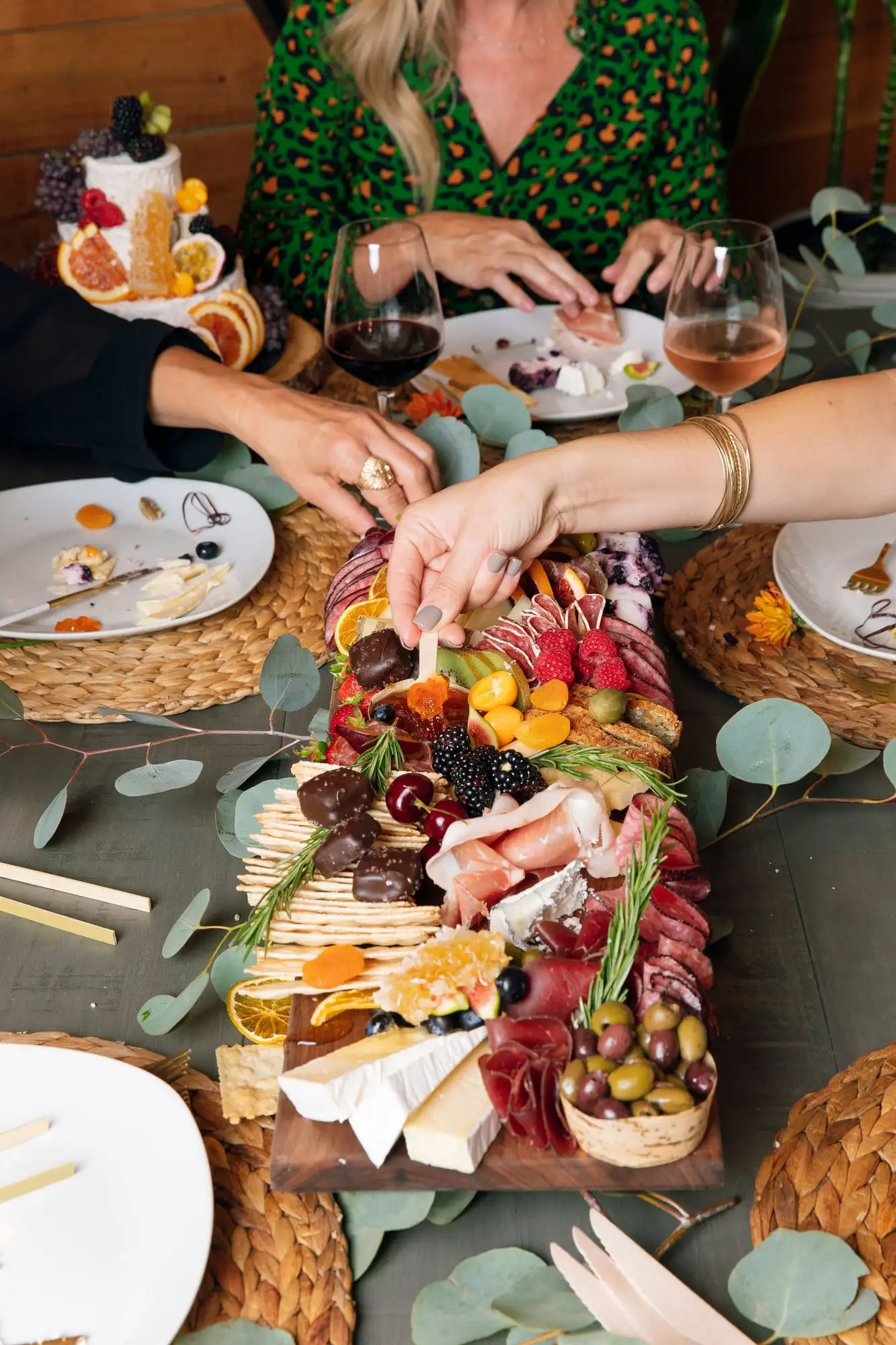 Long wooden picnic board with cheeses, charcuterie, fresh vegetables and honeycomb (view 2)