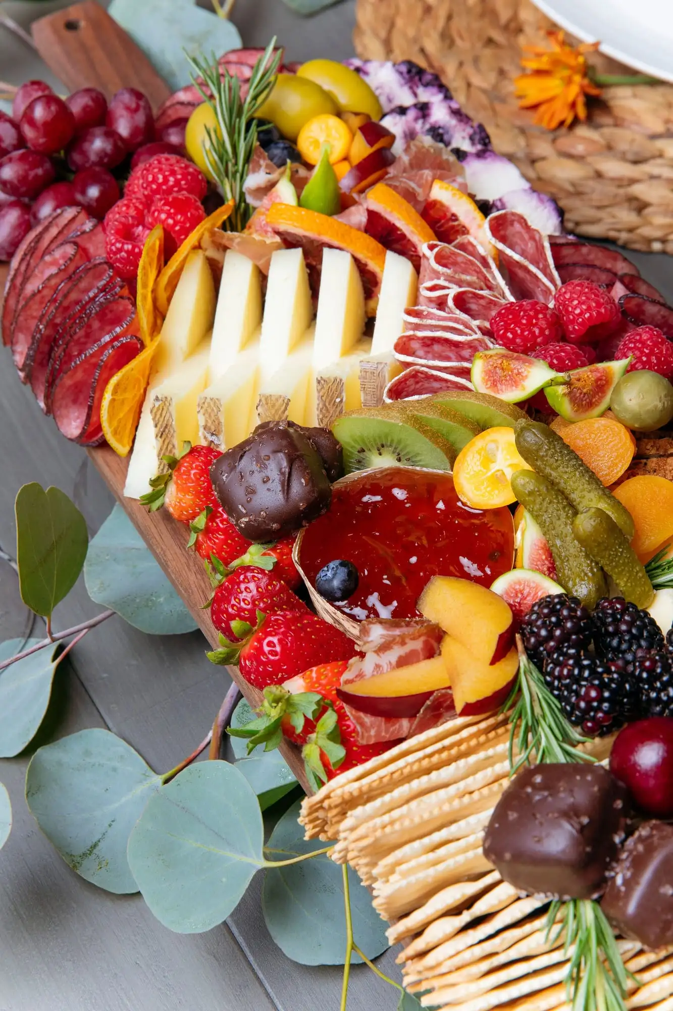 Long wooden picnic board with cheeses, charcuterie, fresh vegetables and honeycomb (view 4)