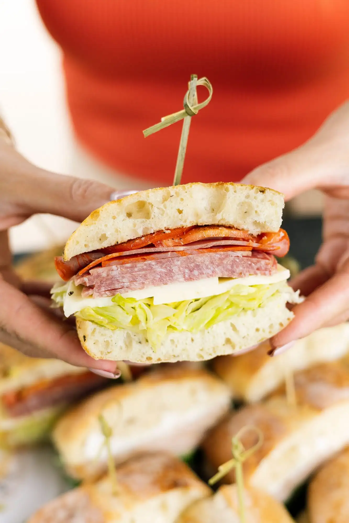 Tray of halved sandwiches wrapped in paper and twine with bags of chips (view 4)