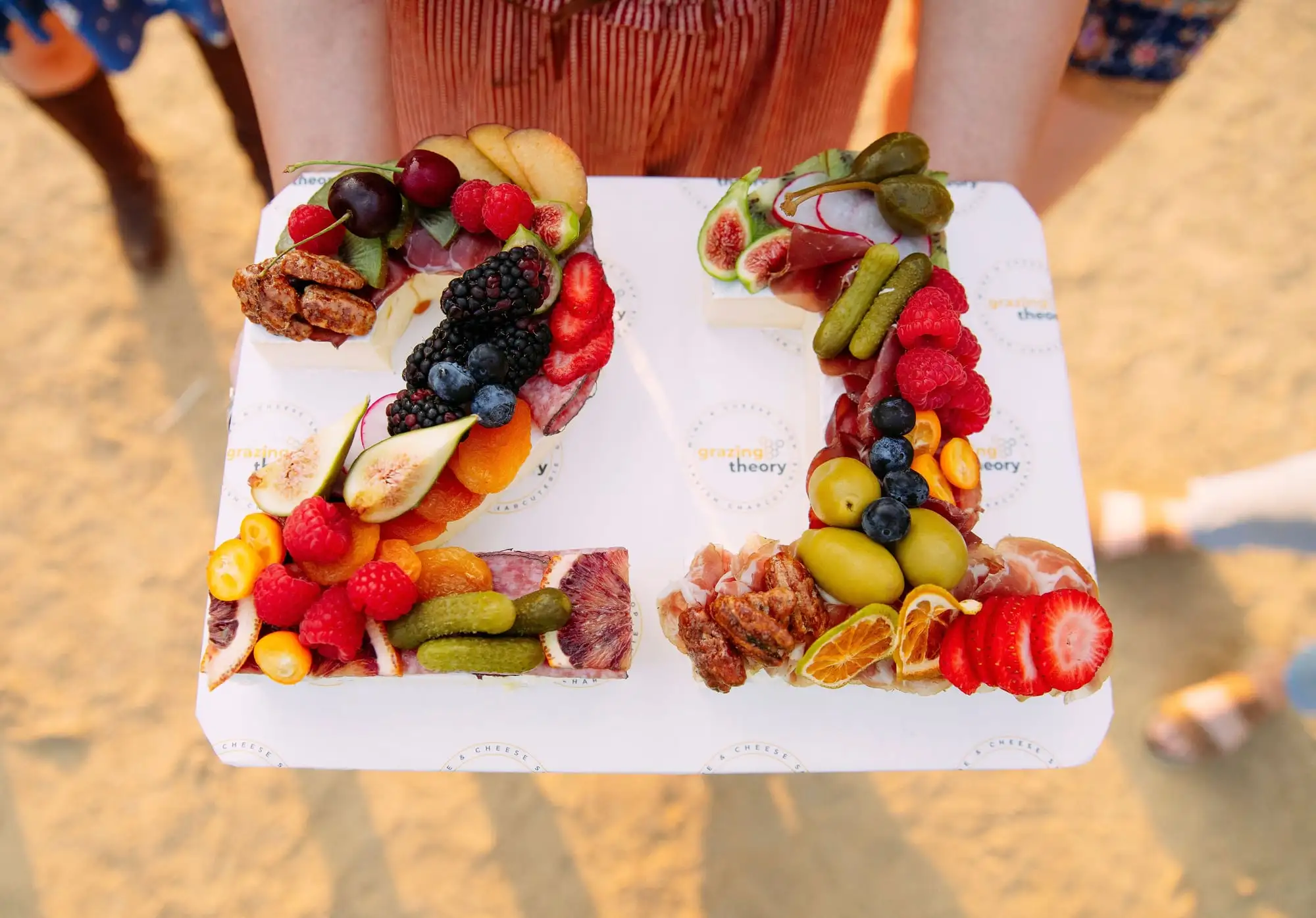 Brie cheese shaped into a number, topped with cured meat, fruit and herbs (view 2)
