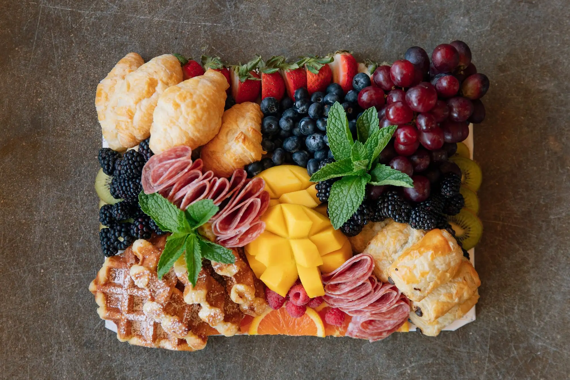 Brunch board with mini croissants, Belgian waffles, fresh fruit and salami