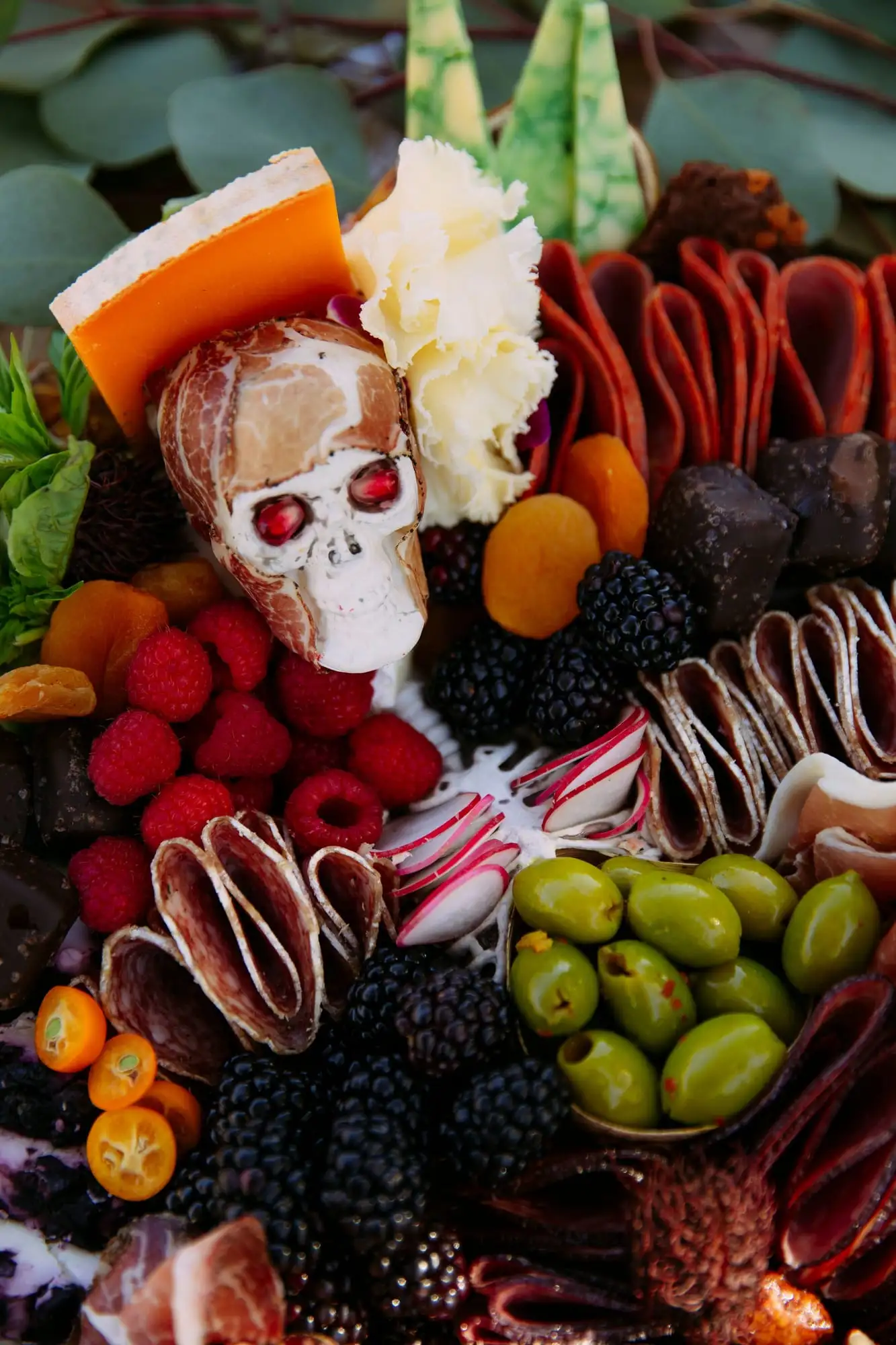 Skeleton charcuterie board for Halloween with a cheese tombstone, salami arms and olive fingers (view 3)