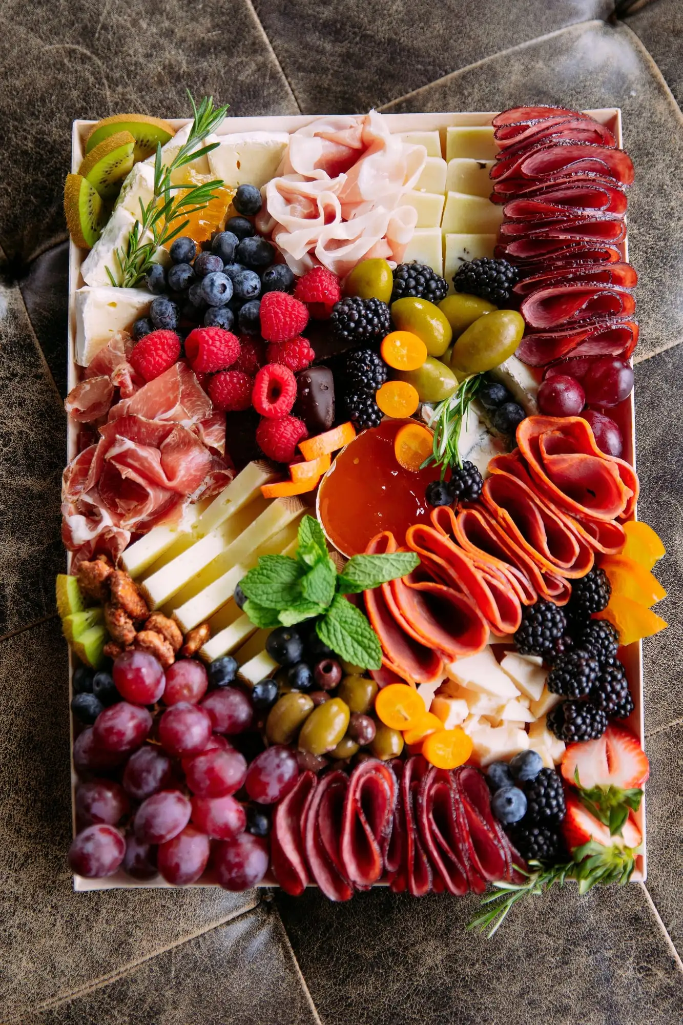 Wooden tray of cheeses, cured meats, fruit and honeycomb for 10 to 12 people
