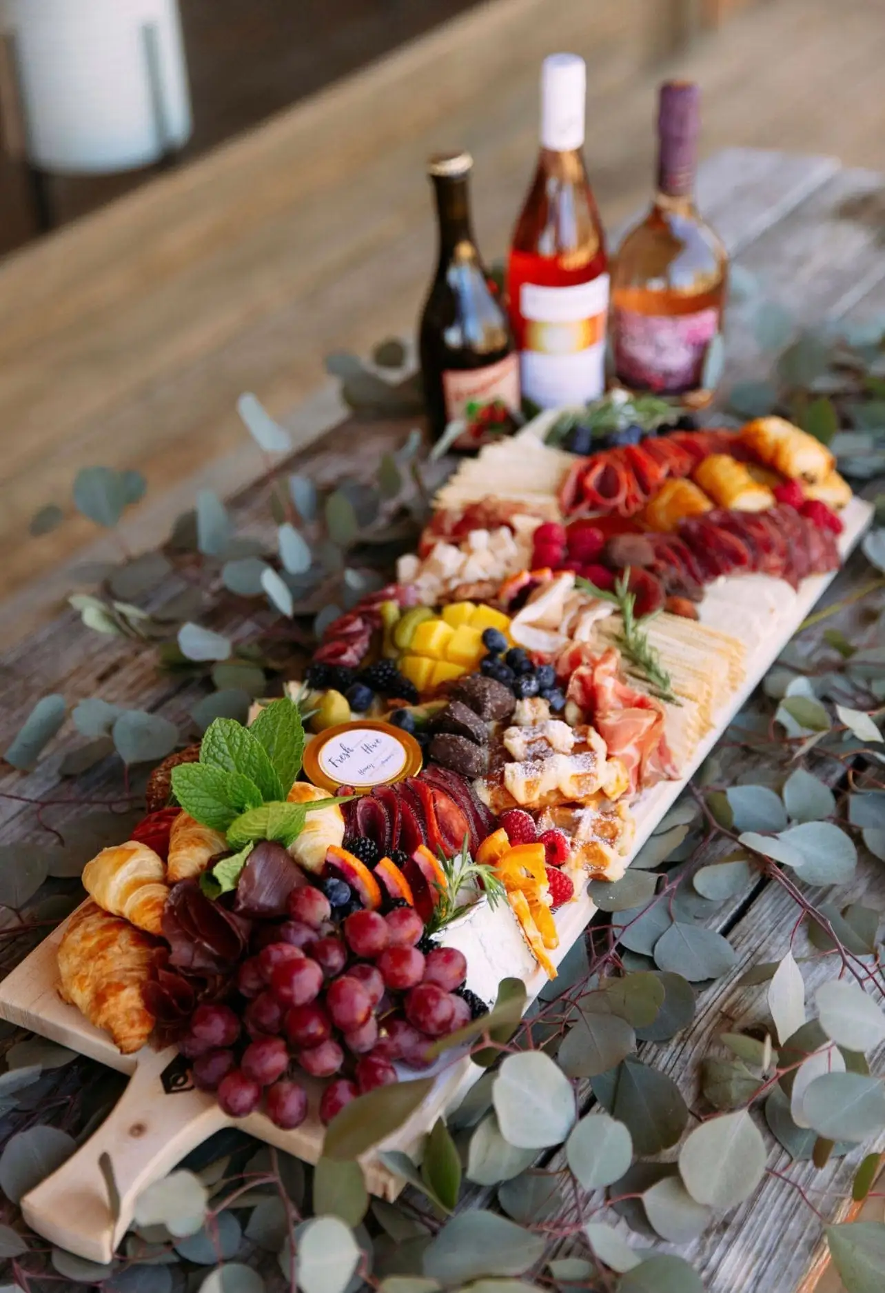 Brunch grazing board with croissants, waffles, cheeses, cured meats and fruit