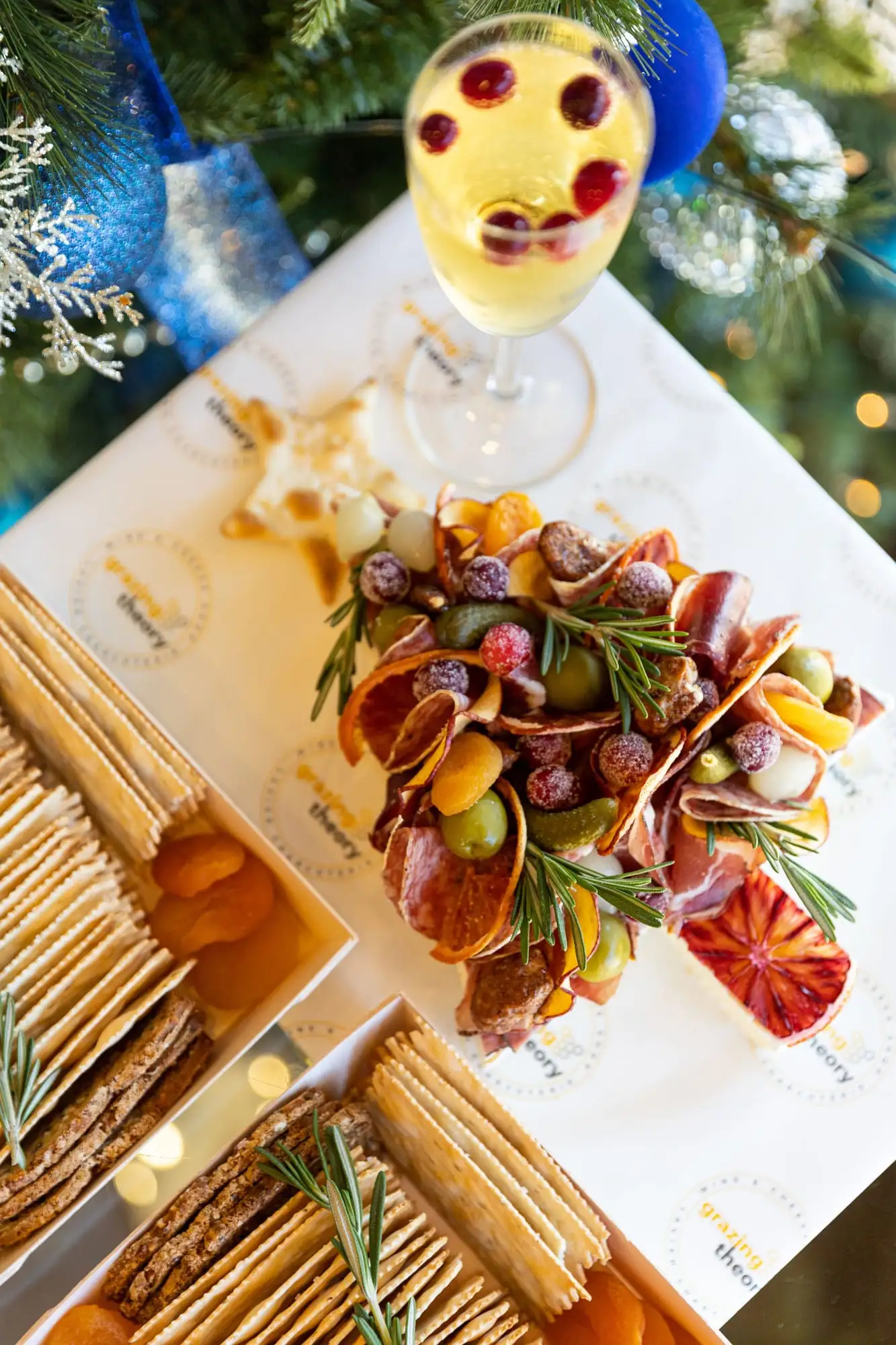 Brie cut into a Christmas tree shape and topped with cured meats and garnishes (view 2)