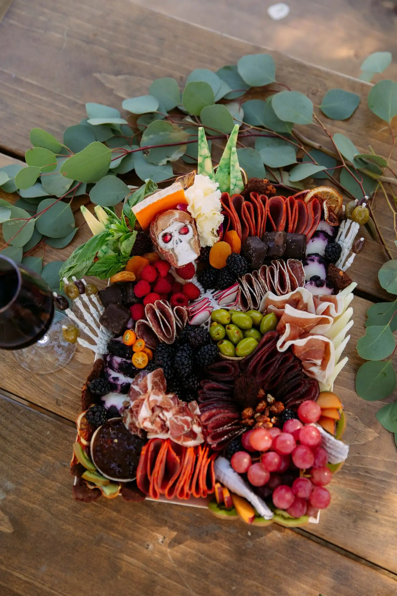 Skeleton charcuterie board for Halloween with a cheese tombstone, salami arms and olive fingers (view 4)