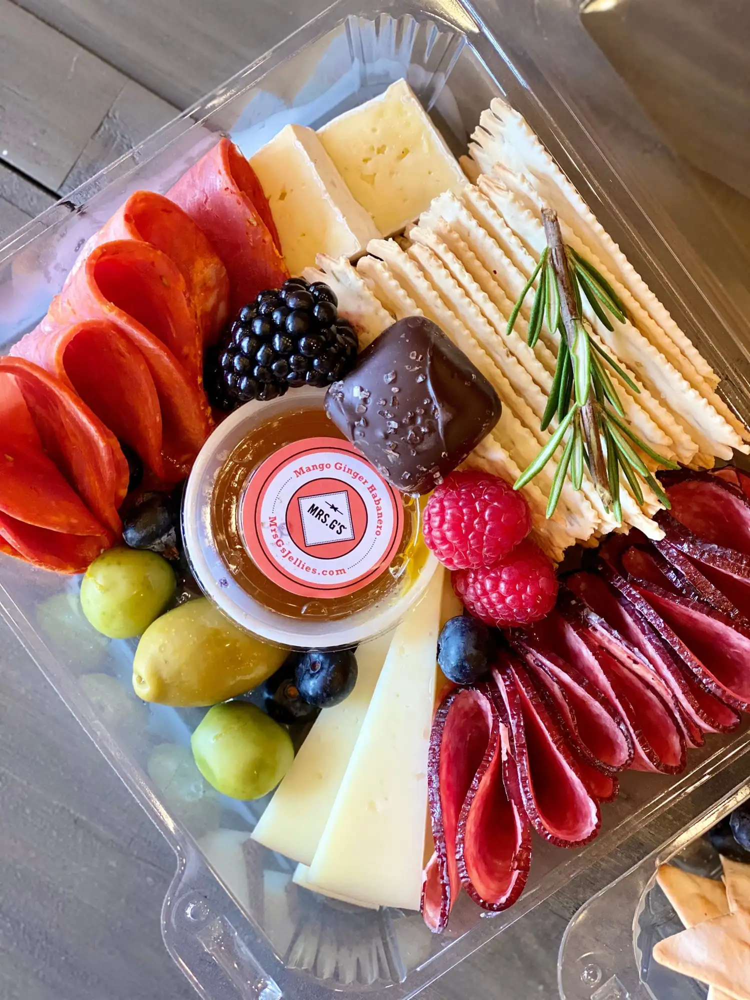 Individual charcuterie box with brie, salami, crackers, olives and fruit
