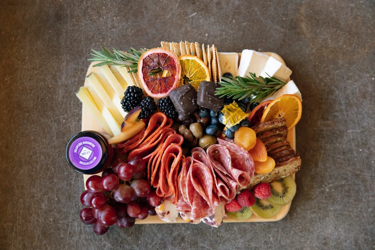 A cheese and charcuterie board with salami, fruit and crackers