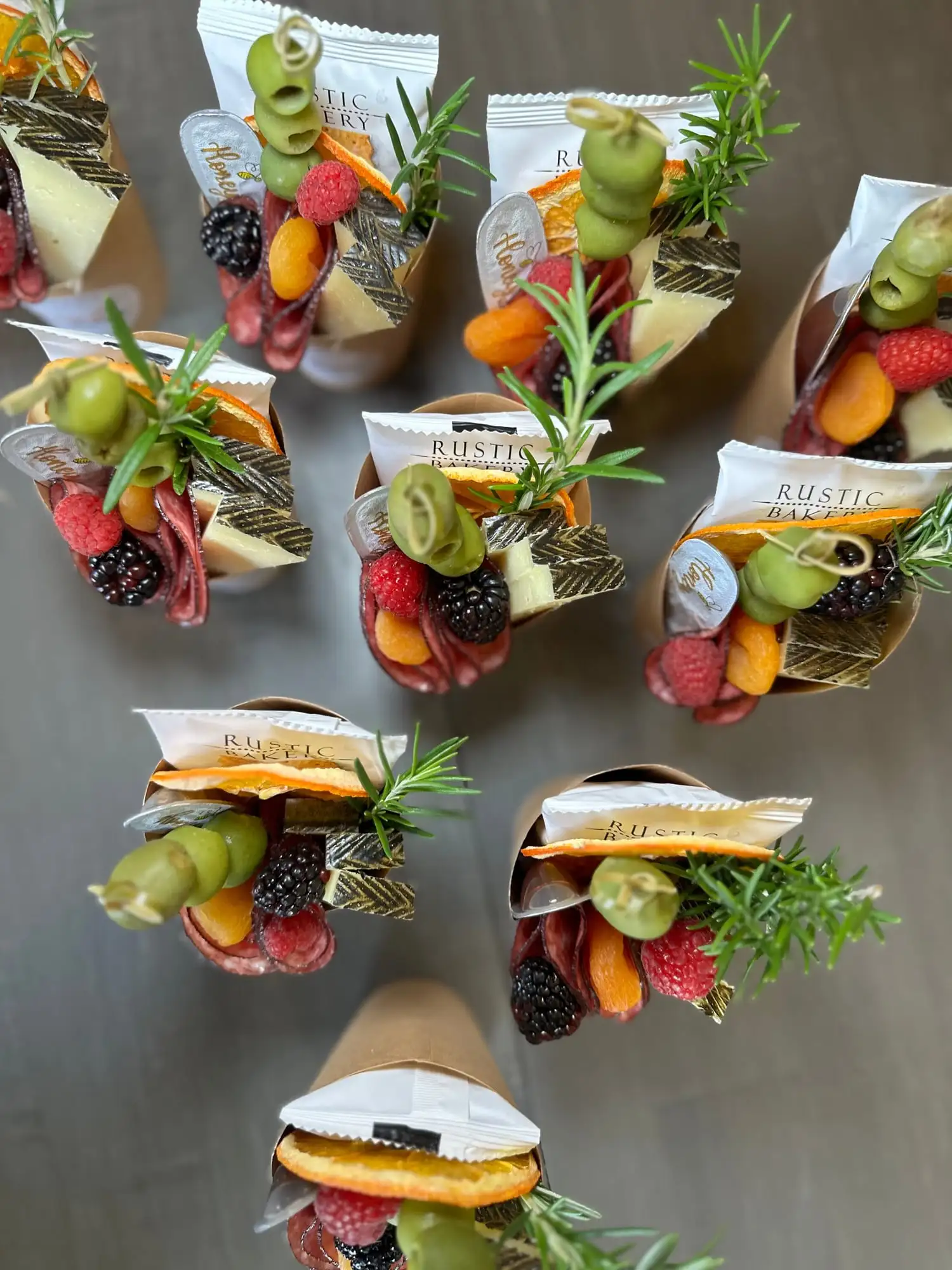 Clear cup filled with cheese, salami, olives, fruit and crackers (view 3)