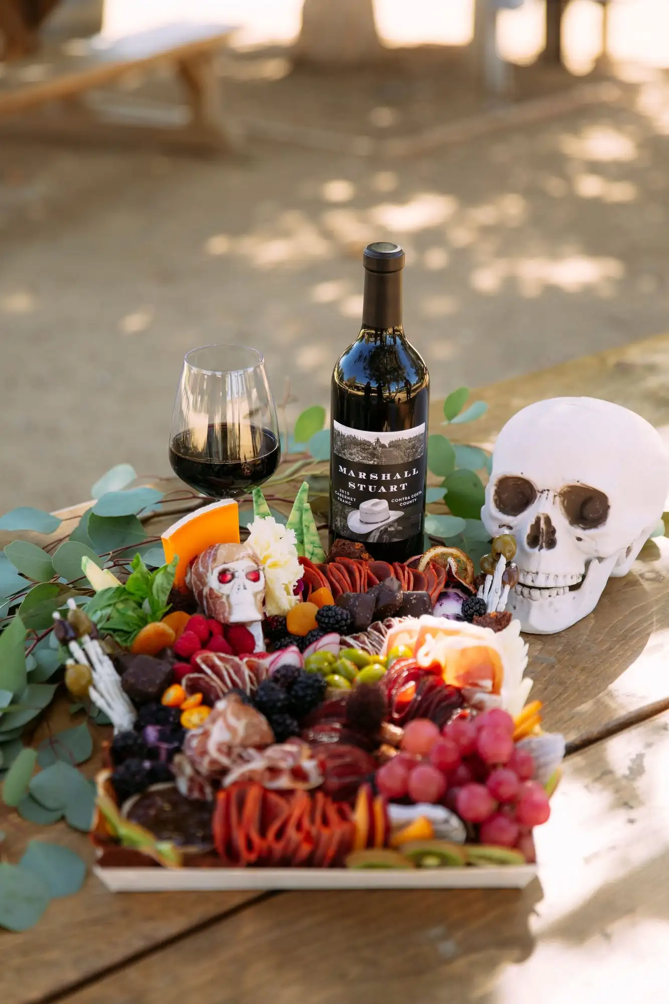 Skeleton charcuterie board for Halloween with a cheese tombstone, salami arms and olive fingers