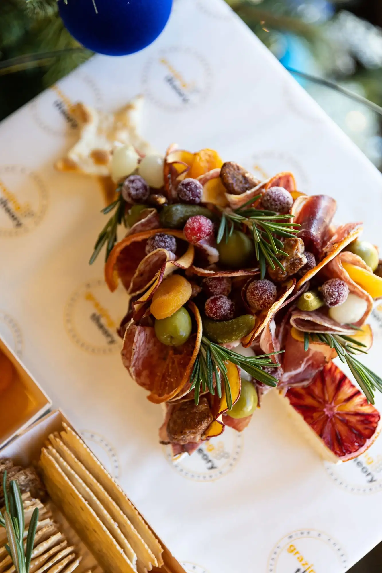Brie cut into a Christmas tree shape and topped with cured meats and garnishes