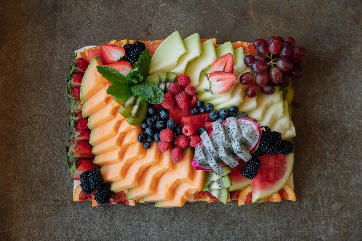 A fruit board with melon, dragon fruit and berries