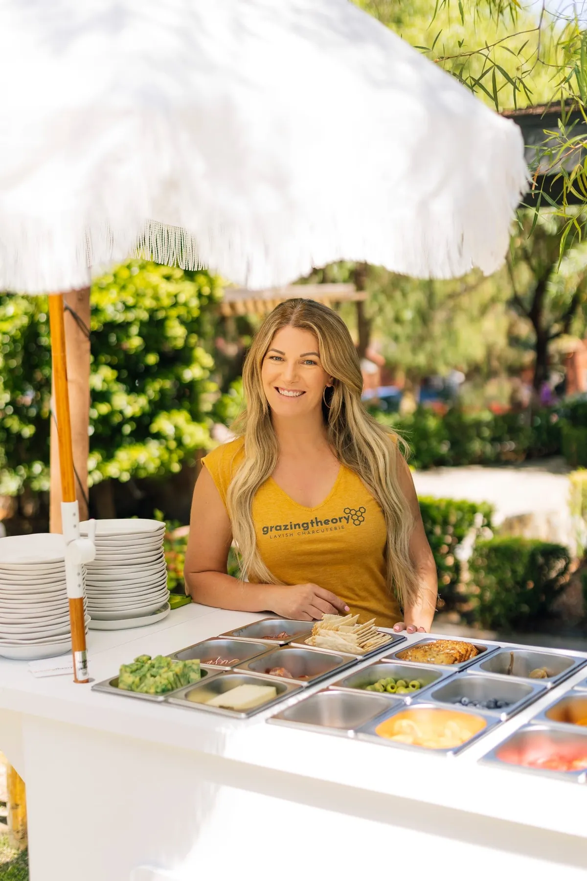 Gina LaMora standing behind the Grazing Theory charcuterie cart