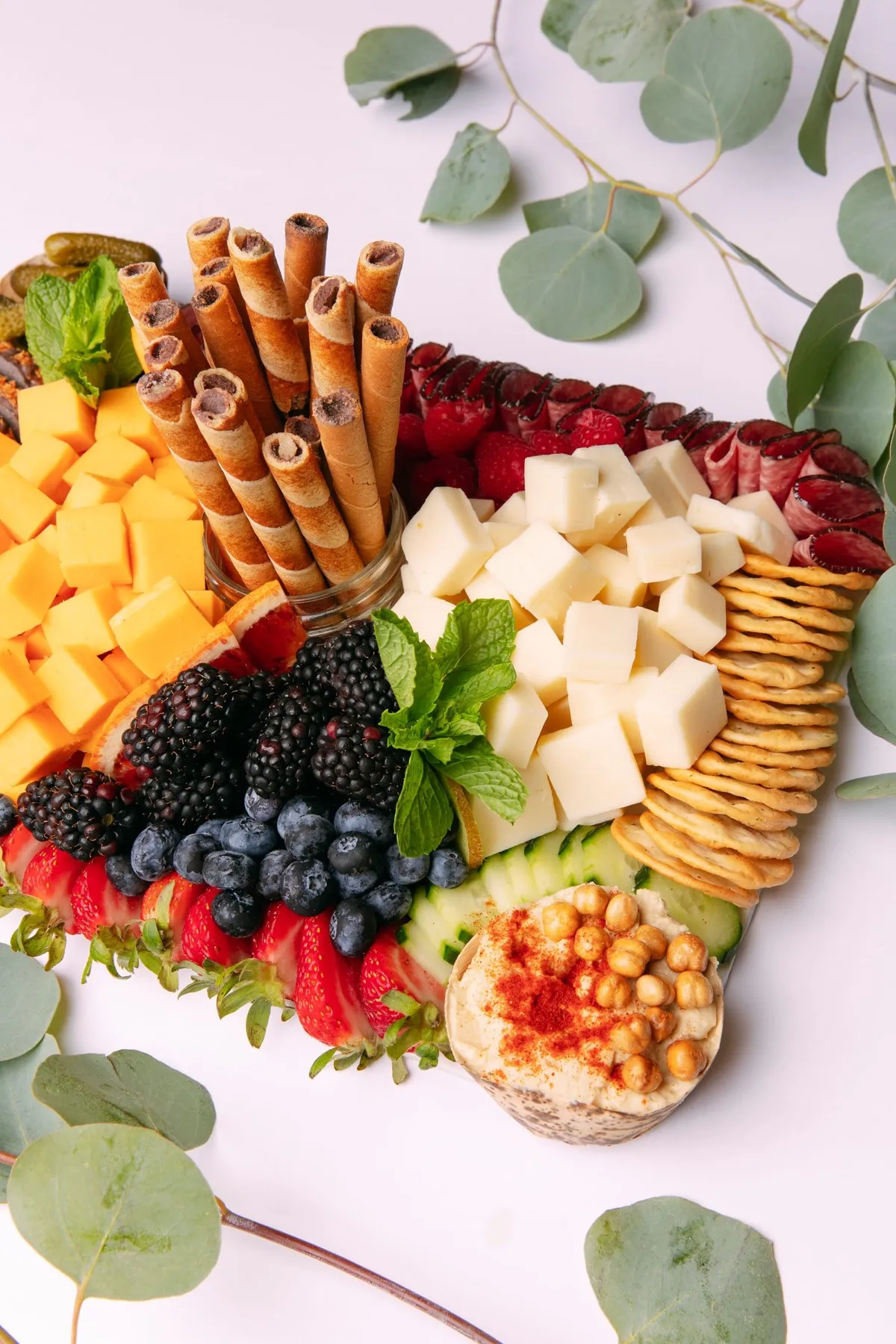 Overhead view of a grazer board with cheddar cubes, berries and crackers