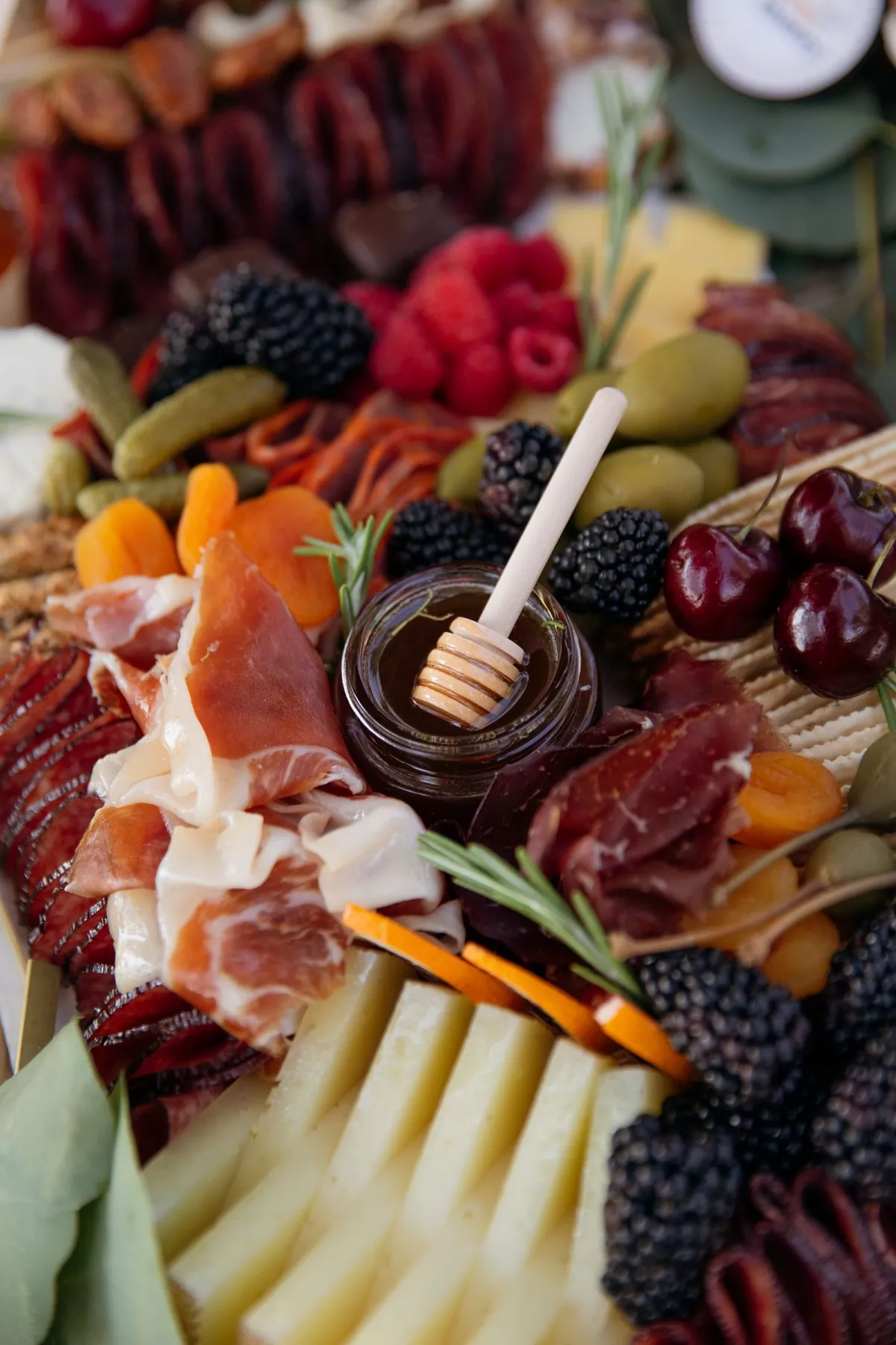 Close-up of honey, prosciutto, berries and cheese on a grazing table