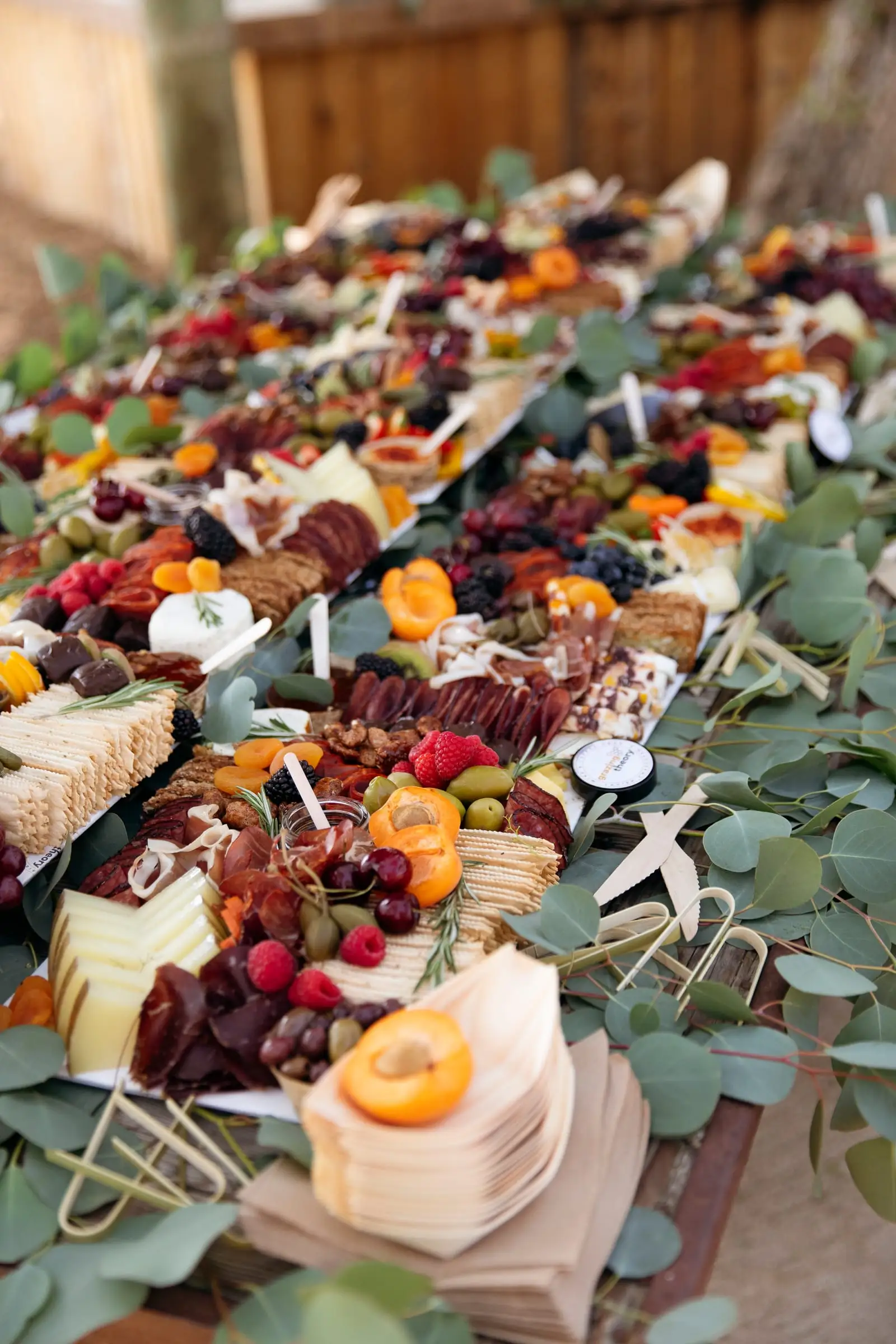 A long grazing table with cheeses, fruit and greenery