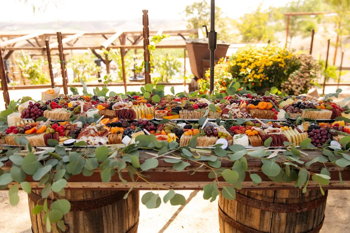 A long grazing table with eucalyptus, cheeses and fruit at a winery