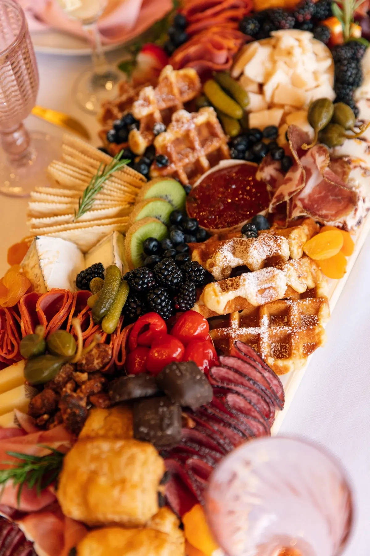 A brunch board with waffles, berries and cured meats