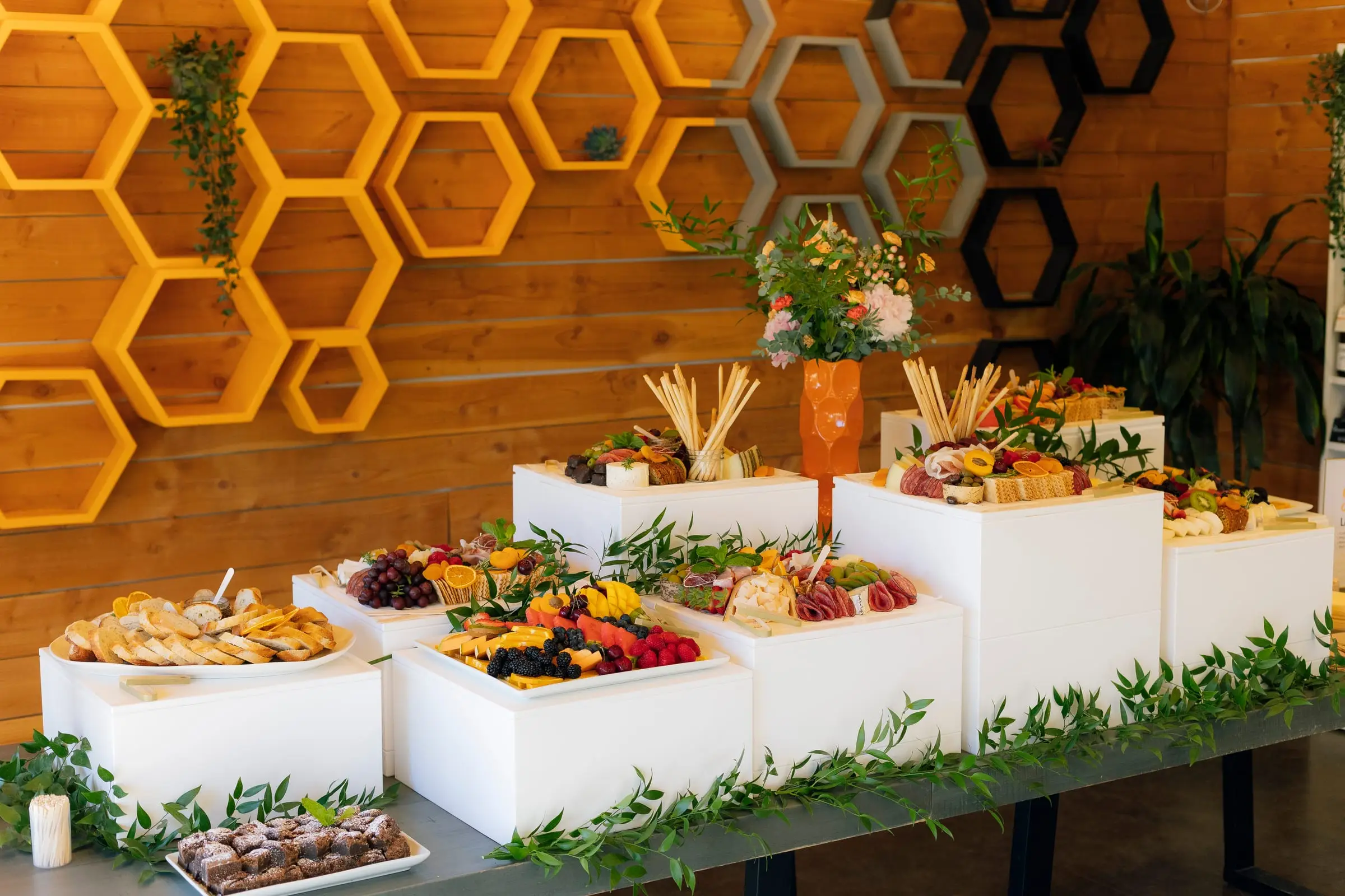 A tiered grazing display on white risers in front of a honeycomb wall