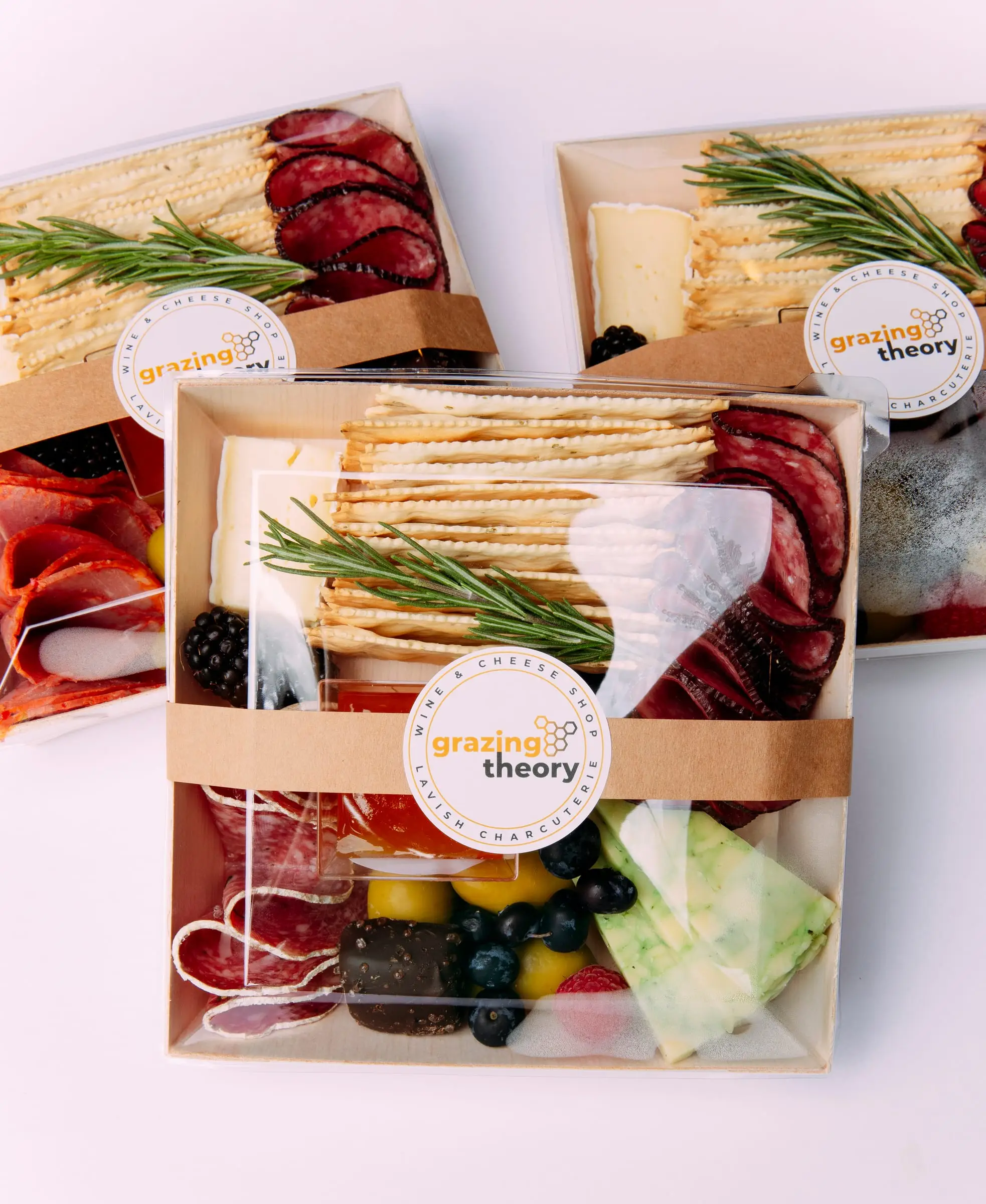 Charcuterie boxes wrapped with Grazing Theory stickers, ready for an office delivery